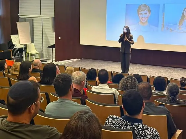 ורד יצחקי כהן מרצה על הבמה מול אולם מלא בכלל ביטוח